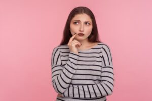 donna dubbiosa con un dito vicino alla bocca