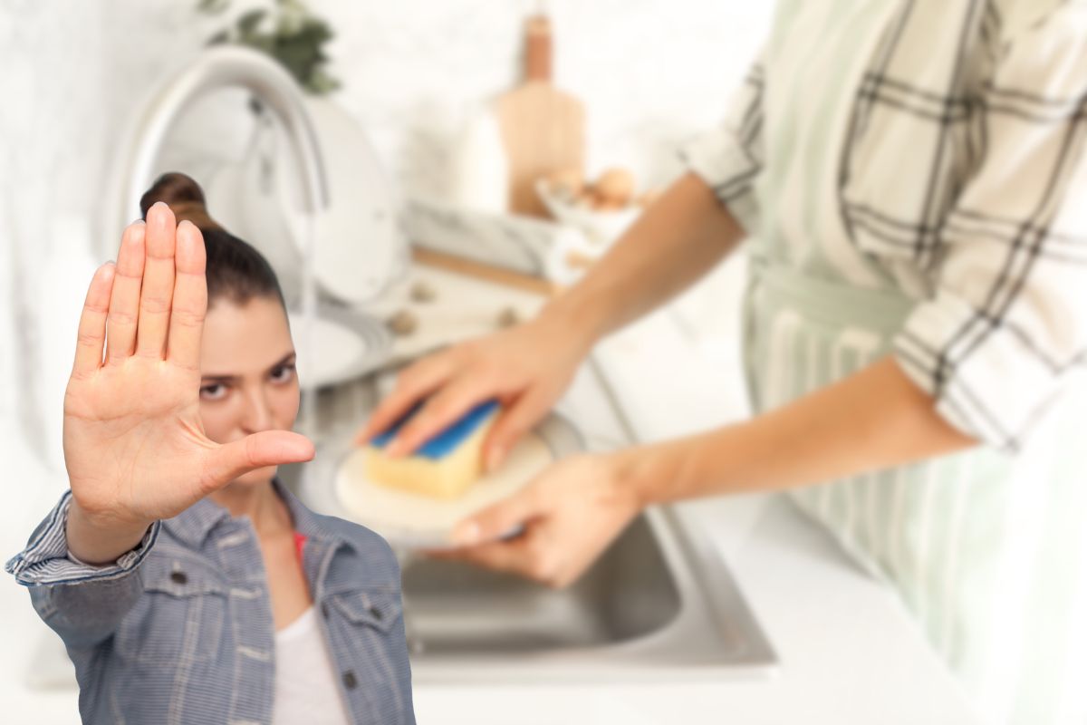 donna che lava i piatti a mano e un'altra che fa stop con le mani