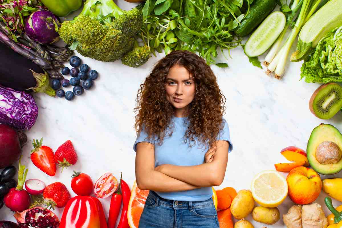 Diversa frutta e verdura sparsa con una ragazza con espressione scettica in primo piano 