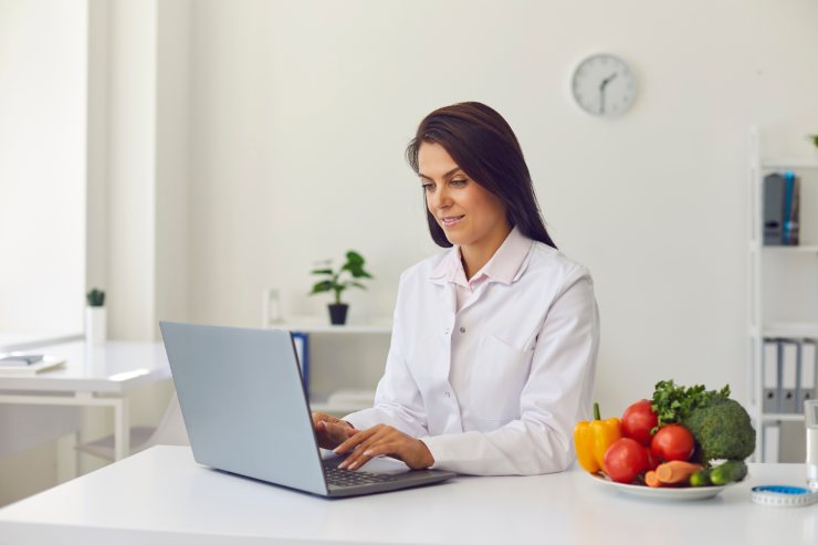 un esperto culinario che scrive al computer con accanto una ciotola di frutta e verdura
